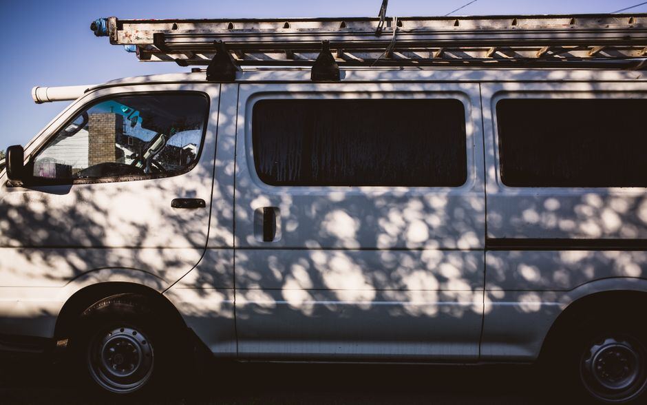 A silver-grey service van with a ladder rack